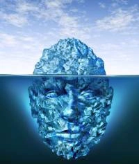 Ein Gesicht im Meer, wobei der obere Teil des Gesichts über der Wasseroberfläche sichtbar ist und der größere Teil unter Wasser verborgen bleibt.