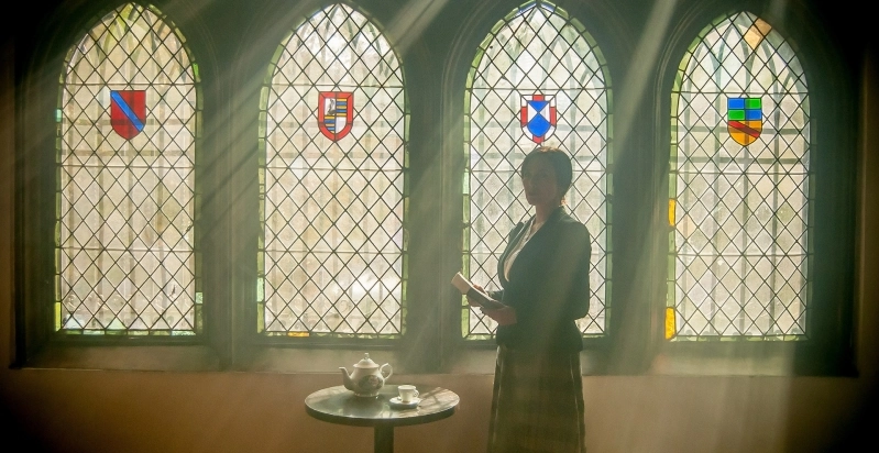 Eine Frau steht in einer Kirche. Durch die Kirchenfenster scheint Licht herein.