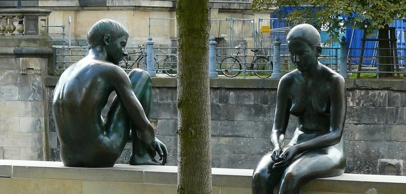 Zwei Bronzeskulpturen von Mann und Frau sitzen abgewandt voneinander auf einer Mauer – ein Sinnbild für Entfremdung und seelischen Schmerz nach einer Trennung.