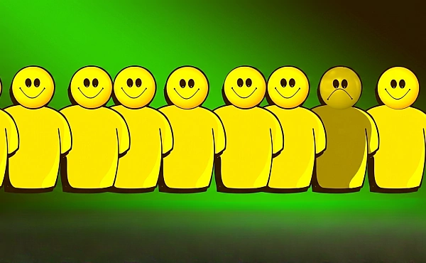 Sieben gelbe Figuren in einer Reihe: Sechs lächeln, während eine in der Mitte ein trauriges Gesicht zeigt und die emotionale Isolation verdeutlicht.