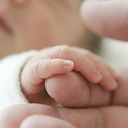 Eine kleine Babyhand umfasst einen Finger als Sinnbild dafür, dass Gefühle in einem geschützten Raum entstehen und wachsen dürfen.