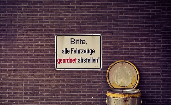 Auf einem alten Schild steht: Bitte, alle Fahrzeuge geordnet abstellen!