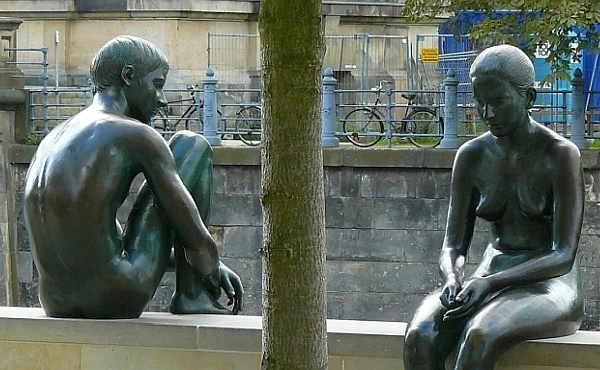 Zwei Bronzeskulpturen von Mann und Frau sitzen abgewandt voneinander auf einer Mauer – ein Sinnbild für Entfremdung und seelischen Schmerz nach einer Trennung.